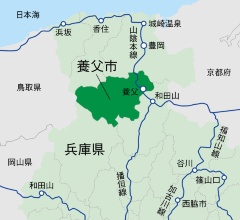養父市は兵庫県北部の但馬地域の中央に位置し、面積は422.91km2。15年8月末日現在、人口2万5241人、世帯数9642世帯。2004年4月1日、兵庫県養父郡の八鹿町・養父町・大屋町・関宮町の4町が合併して成立。14年5月、国家戦略特区指定を受ける。右写真は市役所入り口に張られた特区のポスター(写真:編集部)