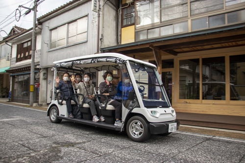 グリーンスローモビリティ実証事業の一コマ。高齢者6人を乗せたゴルフカート型電動車両が、定時定路線バスとして地元住民の外出を促す（写真提供：雲南市）