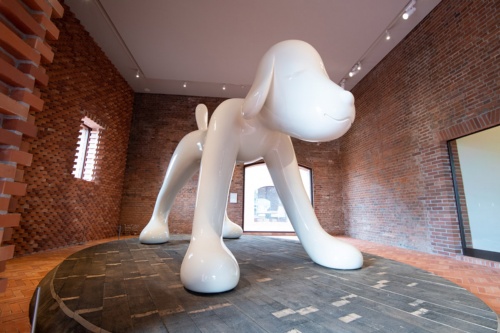 弘前出身のアーティスト奈良美智氏が制作し、2007年に弘前市に寄贈した作品「A to Z Memorial Dog」。楕円形の台座は、レンガ倉庫の屋根裏に使われていた古材を再利用した（写真：村上 昭浩）