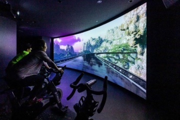 サンガスタジアム by KYOCERAのVR/フィットネスゾーン。壁一面の映像を見ながらエアロバイクを漕ぐサイクルワークアウトなどができる（出所：亀岡市）