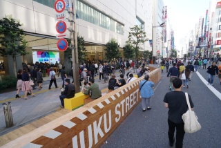 仮設歩道「SHINJUKU STREET SEATS」の様子。2017年に続いての実施となる。車道にも歩行者がいるのは、撮影日が日曜日で歩行者天国だったため（写真：日経BP総研）