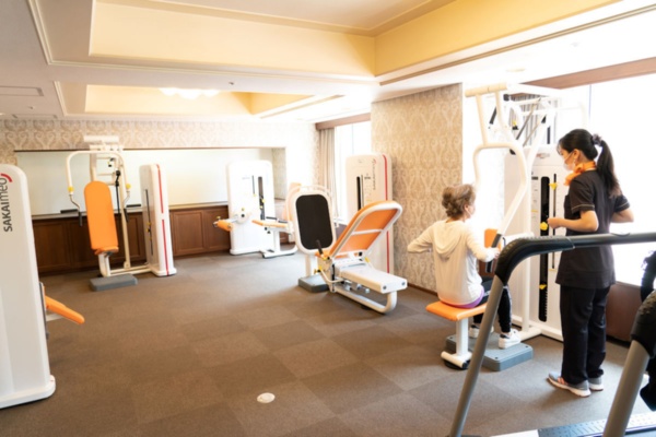 ゆったりとしたトレーニングルームに、酒井医療のパワーリハビリ用機器6機種を用意する。一般的なトレーニングマシンと見た目は似ているが、負荷が軽いという特徴を持つ。筋肥大ではなく、関節の柔軟性や関節可動域の回復を目的とする。軽いリズミカルな動きで、弱った全身の神経と筋肉を再び活性化させるという(撮影:大亀 京助)