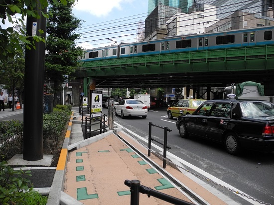 (写真2)新橋のステーションは大手町と違って車道側にせり出させる造り。車道との間はチェーンゲートで仕切る。ただそのほかは、大手町と共通だ。車道との間に縁石を埋め込み、ステーション部分を着色し、車道との違いを強調する(写真:茂木俊輔)