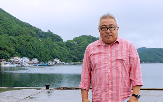 阿曽浦漁港に立つ小川伸司氏。サバの養殖現場に向かうところ(撮影:筆者)