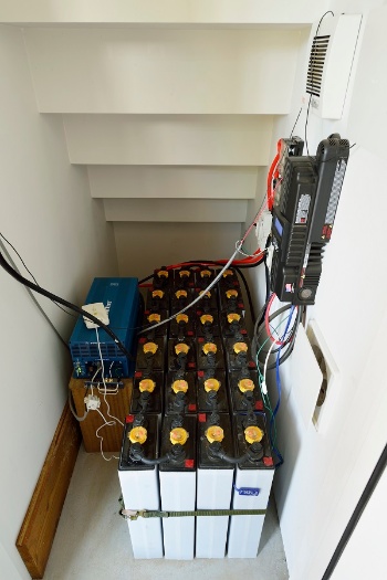 フォークリフト用の鉛バッテリーを24台連結して使っている。右側の壁の黒い装置が充電コントローラー(写真:大槻 茂)