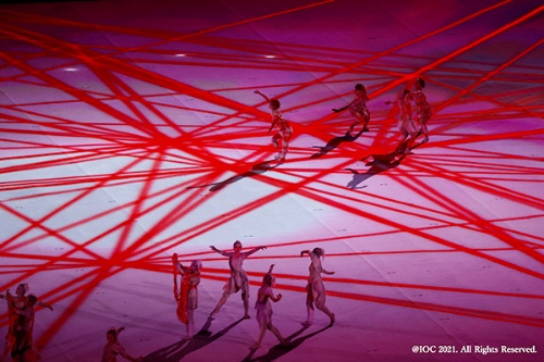 東京オリンピックの開会式のワンシーン。ダンサーが赤いロープで繋がりながら踊る場面でフィールドに投影された赤い線の映像は、このプロジェクターの特性がよく表れた表現だったとする（写真提供：パナソニック）
