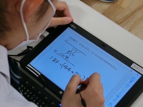 生徒はタブレット型のパソコンとペンで課題に取り組む。多くの生徒は戸惑う様子もなくパソコンを使っていた