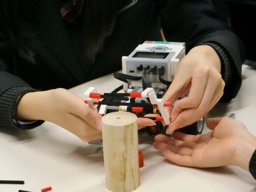 ロボットのアームの動きを検討しながらブロックを組む生徒たち